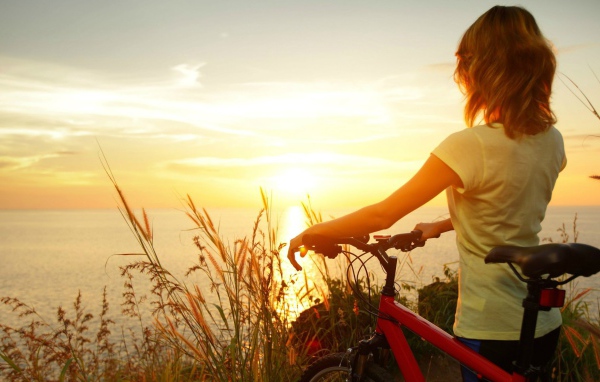 Девушка с велосипедом смотрит на закат