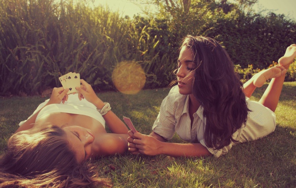 Девушки играют в карты на газоне