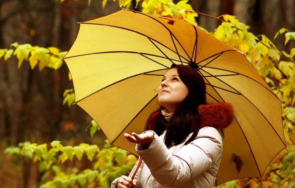 Милая девушка ловит капли осеннего дождя