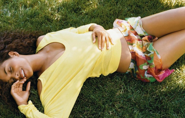 Мулатка в желтой футболке лежит на траве