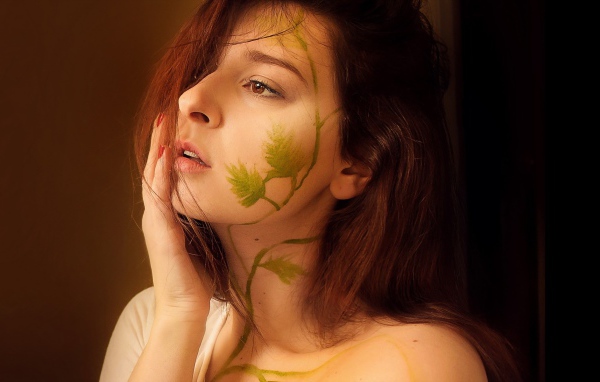 Рисунок зеленых листьев на лице и шее девушки