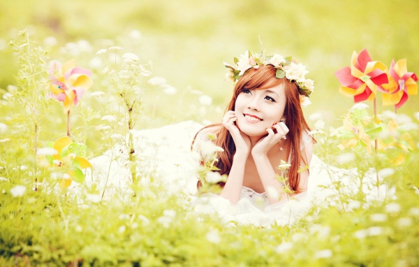 Рыжая японская девушка лежит в поле цветов