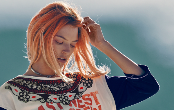 Рыжая девушка на ветру поправляет волосы