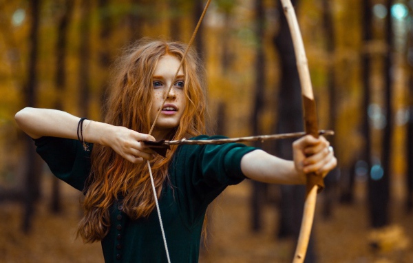 Рыжая девушка целится из лука