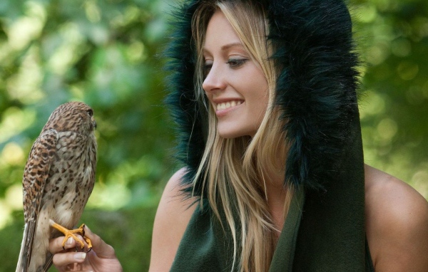 Девушка в меховой накидке держит на руке птицу