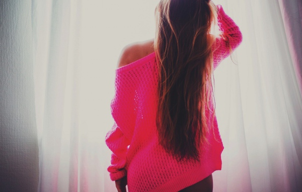 Девушка в розовой кофте стоит спиной