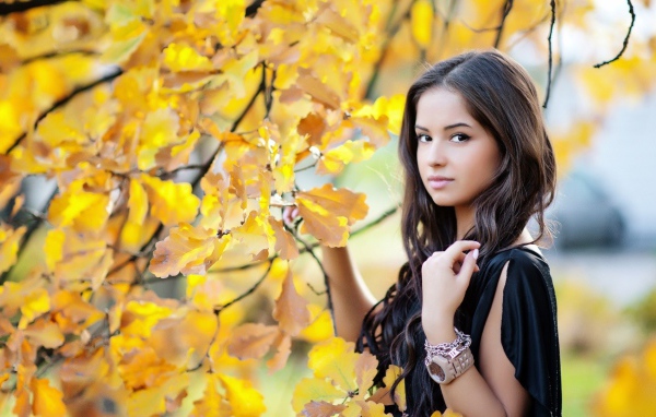 Молодая брюнетка у осеннего дерева