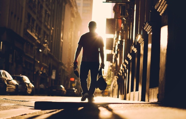 Мужчина идет по улице навстречу солнцу
