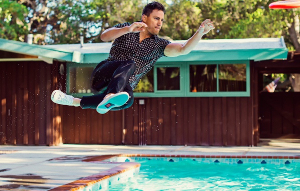 Мужчина прыгает в бассейн в одежде