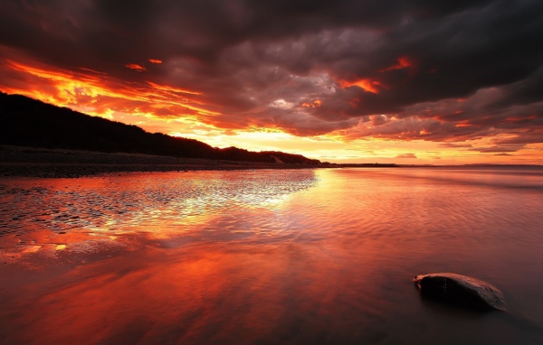 Камень на мелководье на фоне красного заката