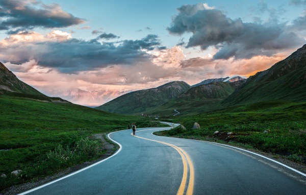 Одинокий путник на шоссе среди гор