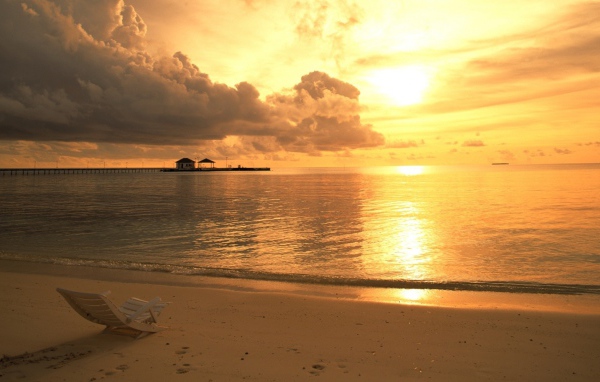 Одинокий шезлонг на пляже на закате