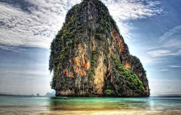 Оранжевая скала в зарослях у берега