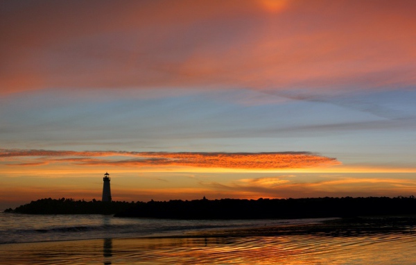 Силуэт маяка на фоне оранжевых облаков