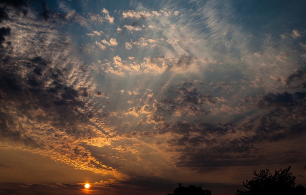 Солнце на закате освещает перистые облака