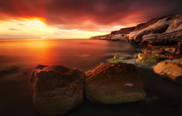 Два больших камня на берегу моря на закате