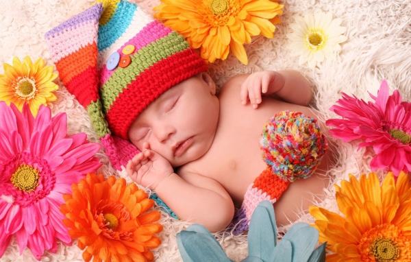 Малыш спит в постели среди цветов
