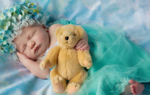 Ребенок спит с медвежонком в руке