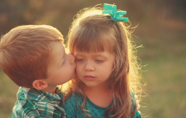 Мальчик целует сестренку в щеку