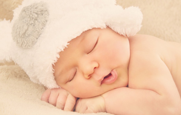 Спящий ребенок в белой шапке