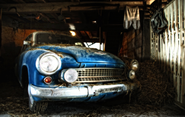 Старый автомобиль присыпан сеном в сарае