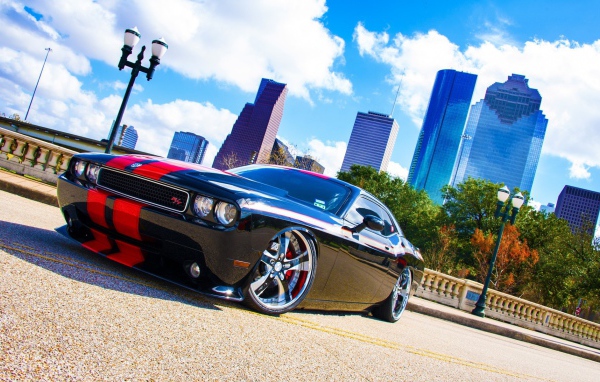 Черный Dodge Challenger с красными полосами на фоне небоскребов