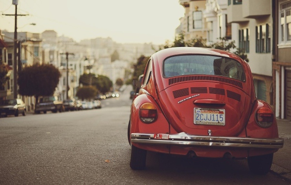 Красный Volkswagen Beetle припаркован на краю улицы
