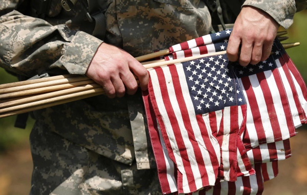 Солдат держит в руке флаги США