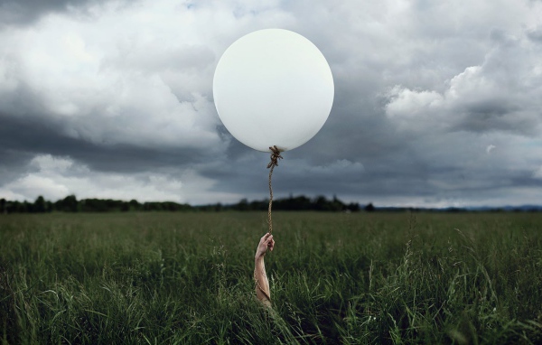 Рука с шаром среди поля