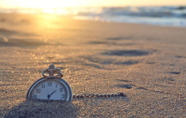 Часы на цепочке лежат в песке