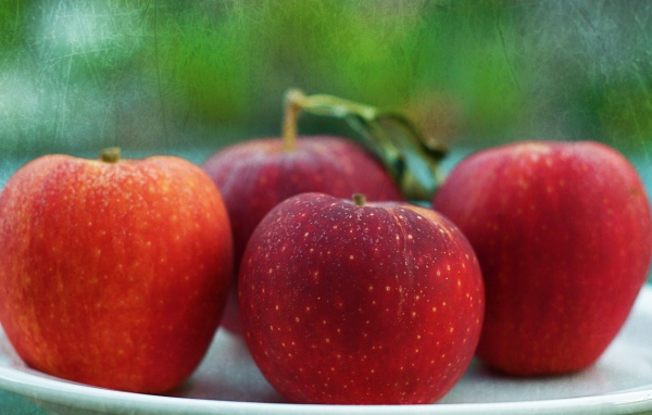 Четыре красных яблока на тарелке