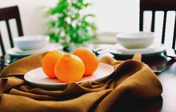 Три апельсина на белой тарелке