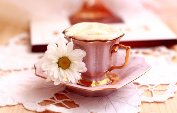 Кофе с пенкой и ромашка на блюдце