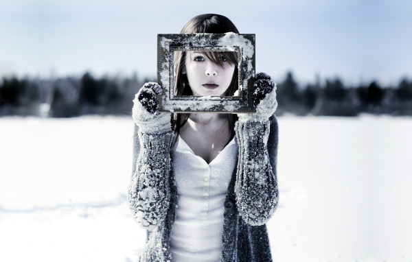 Девушка держит в руках фоторамку в снегу