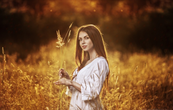 Девушка в белом платье держит в руке колоски