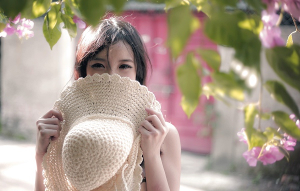 Азиатская девушка прикрыла лицо шляпой