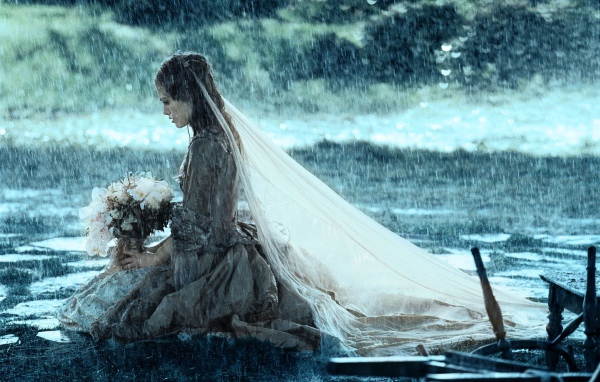 Невеста сидит на коленях под дождем