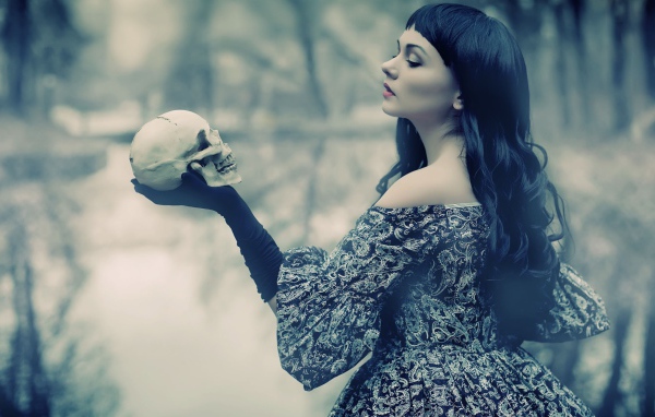 Брюнетка держит в руке череп
