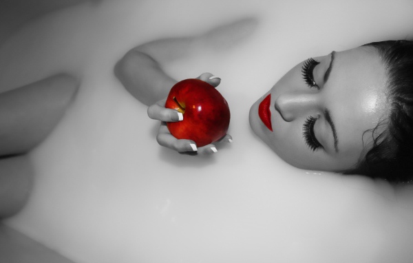 Девушка ест яблоко лежа в ванной