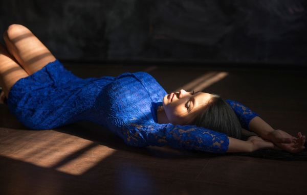 Девушка в голубом кружевном платье лежит на полу