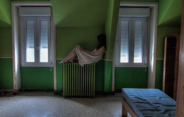 Девушка в ночной рубашке сидит на батарее