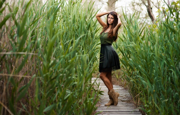 Девушка на деревянной дорожке среди камышей