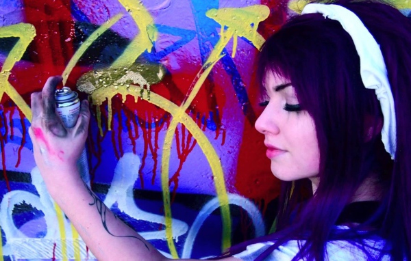 Девушка рисует граффити на стене