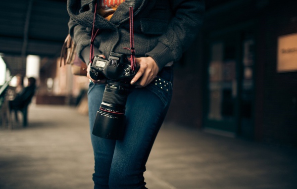 Девушка фотограф с профессиональным фотоаппаратом Canon