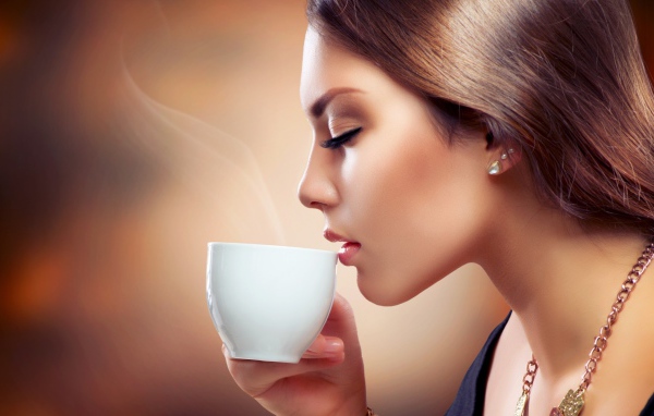 Девушка вдыхает аромат кофе