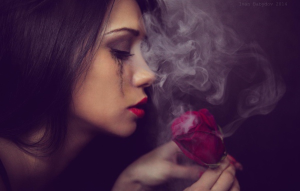 The girl looks at smoking rose
