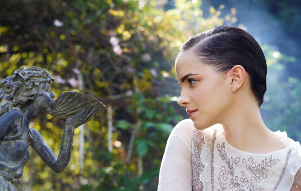 Девушка смотрит на скульптуру в саду