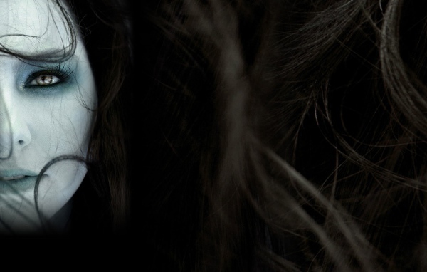 Лицо девушки среди волос на темном фоне