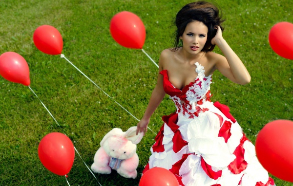 Девушка с игрушкой среди красных воздушных шариков