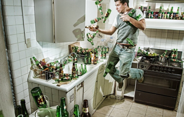 Мужчина среди бутылок пива на кухне